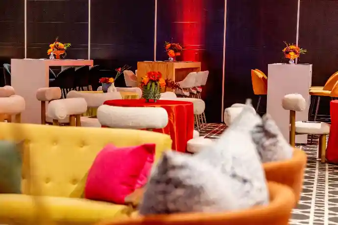 Corporate lounge setup with yellow and orange furniture under red lighting