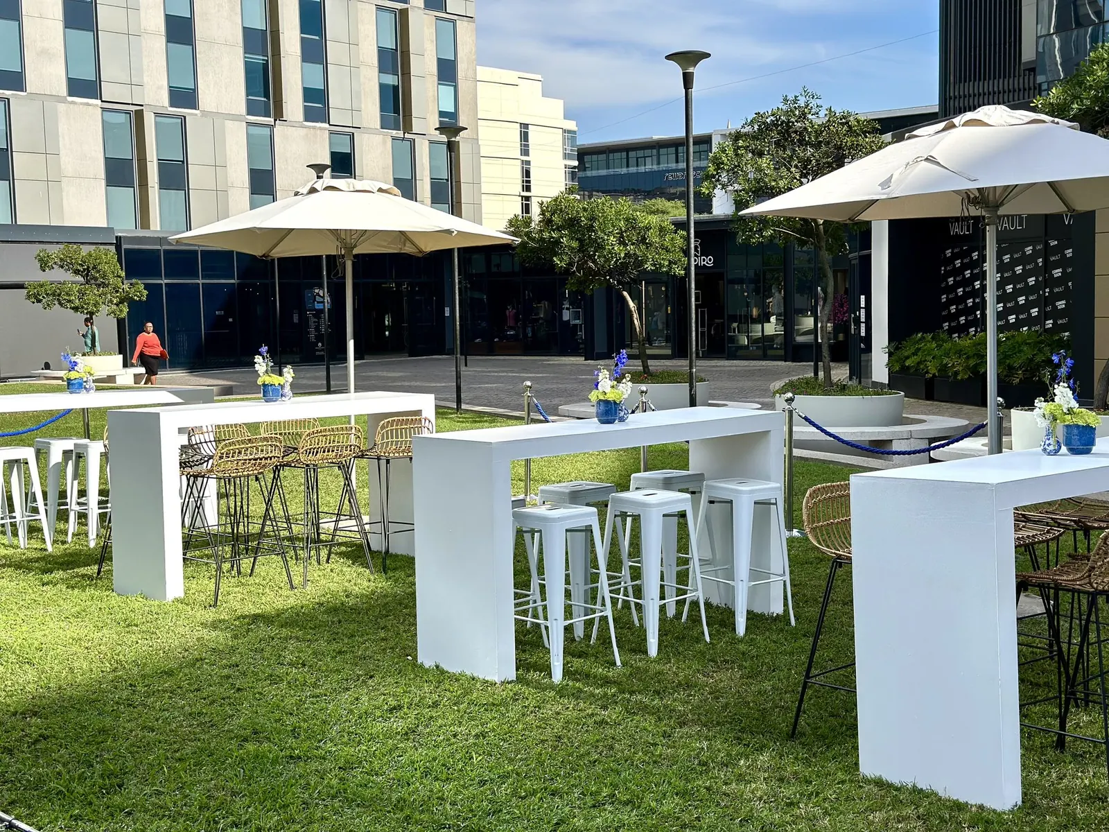 White cocktail tables and umbrellas at a garden event