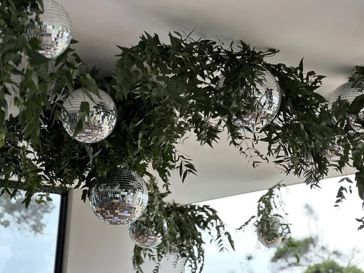 Suspended greenery and mirror balls at a company celebration